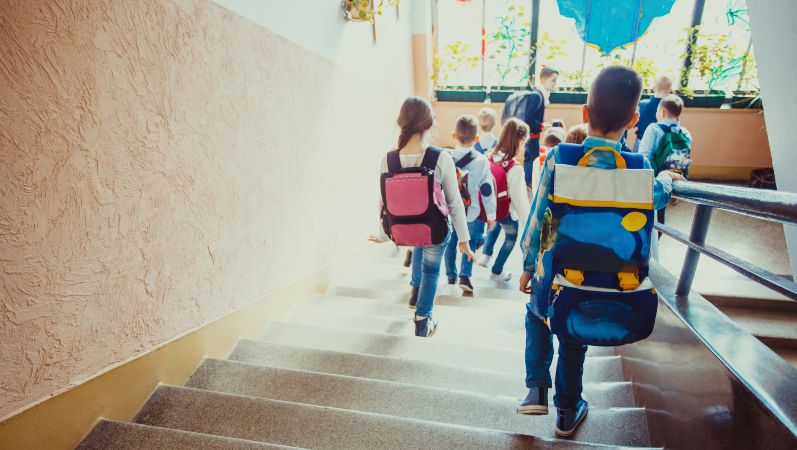 Symbolfoto: Schülerinnen und Schüler verlassen ein Schulgebäude über eine Treppe.