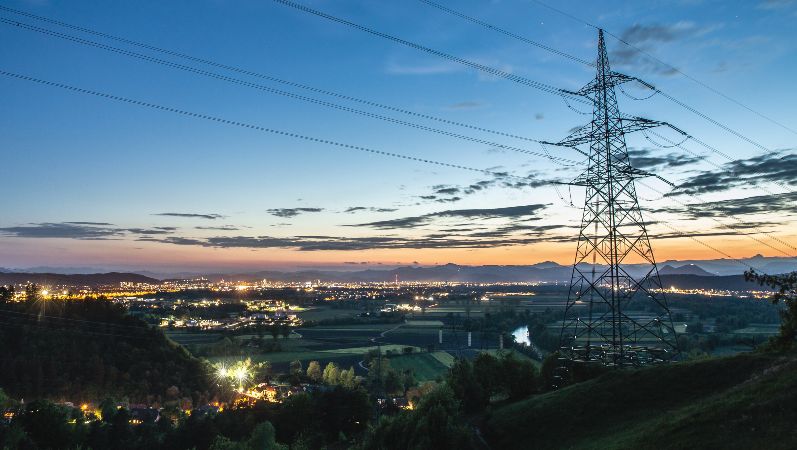 Überblick über eine Landschaft, Strommast und Stromleitungen im Vordergrund.
